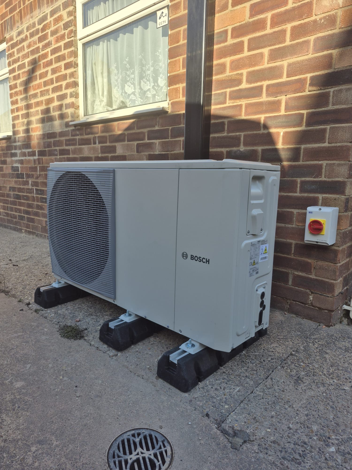 Bosch air source heat pump beside a brick house