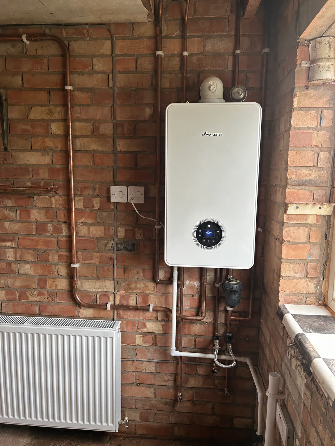 Worcester Bosch boiler and copper pipework on a brick wall